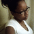 Pixelated image of a person with dark hair wearing glasses and a white shirt, viewed from the side against a light background.