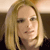 Static pixelated image of a person with light brown hair, fair skin, and dark eyes, wearing a dark top against a light background.