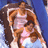Pixelated image of a woman with long brown hair wearing a white sleeveless top and light blue bottoms against a blue background.