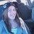 Pixelated image of a person with long dark hair wearing light blue clothing against a blue and white background.