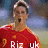Pixelated image of a person in a red sports jersey with white text and a number, against a blurred outdoor background.