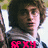 A pixelated image of a person with brown hair and glasses, wearing a dark jacket over a light shirt, with red text and heart symbols overlaid.