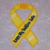 A yellow ribbon with a black diagonal stripe on the left side, next to pink pixelated text reading 'God Bless Our Soldiers' on a black background.