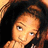 Pixelated close-up of a person with dark hair and light skin, wearing a black top against a warm-toned background.
