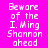 Pixelated text on bright pink background with green highlight bars shifting across lines of 'Beware of the I. Ming Shannon ahead' in white block letters.