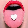 A close-up of a mouth with red lips, a pink tongue, and a white heart-shaped cutout on the tongue.