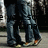 Two figures in dark blue jeans stand side-by-side on a light gray surface with blurred background elements.