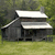 Pixelated image of a dark gray house with white roof sections on a green grassy background.