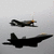 Two aircraft silhouettes against a light gray background with subtle pixel noise.