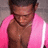 A pixelated image of a person wearing a pink jacket and dark necklace, with short dark hair against a gray background.