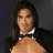 A pixelated image of a person with long dark hair wearing a black jacket and bow tie against a gray background, alongside stacked text elements on red and blue backgrounds.