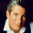 A pixelated image of a person with short light brown hair wearing a white collared shirt, next to green text on a dark background.