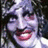 Pixelated image of a person with curly hair and a wide smile on a dark red background with green text.