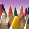 A close-up of multiple colored pencils with sharpened tips arranged in a row against a purple gradient background.