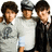 Three pixelated figures stand side-by-side, each with distinct clothing and hairstyles against a plain background.