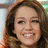 Pixelated close-up of a smiling person with brown hair, visible teeth, and light skin tone against a blurred background.