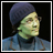 Pixelated static image of a person wearing a dark beanie and blue jacket against black background with white border.