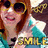 A person with brown hair wearing yellow sunglasses and a teal shirt, smiling beneath the word SMILE in gold letters.