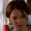 A four- shows a person with brown hair in a bun, wearing a red and blue garment, against a light background with vertical lines