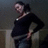 Pixelated image of a person in dark clothing with one hand on hip, standing against muted background.