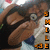 Pixelated image of two figures in close embrace, one with dark hair and brown skin, the other with light skin and white clothing, with orange and black symbols on the right edge.