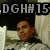 Pixelated image of a person with brown skin tone wearing a light-colored shirt, positioned below a black banner with white text reading "DGH#15" against a blurred background.