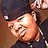 Pixelated close-up of a person wearing a dark cap and dark clothing, with a light brown background.