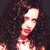 A pixelated close-up of a person with long dark hair, wearing a red top, against a dark background.