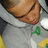 Pixelated close-up of a person's face with closed eyes, wearing a gray shirt with green and yellow accents.