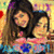 Two women with long brown hair pose together in a pixelated image; one wears pink clothing, the other blue and white. Background features red hearts and purple text.