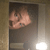 Pixelated image of a person with light skin tone holding a small object near their face, set against a dark background with a light gradient on the right.