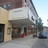 Pixelated static image of a building facade with a dark doorway, arched windows, and a red element near the ground level under a light sky.