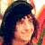 Pixelated static image of a person with dark hair and warm-toned background colors, likely from an old digital photo or low-resolution source.