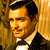 Pixelated portrait of a man in a black suit with a white shirt and black bow tie, set against a golden-brown textured background.