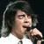 A pixelated image of a person singing into a microphone with orange hearts and text on purple background.