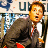 Static pixelated image of a man in business attire with partial background text and color accents, likely from a movie or TV show reference.