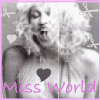 Black-and-white image of a person with voluminous curly hair, wearing a heart symbol over the chest, with 'Miss World' text in pink below.
