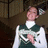 A pixelated image of a person in traditional attire holding an object, with yellow text on dark green and gray backgrounds.