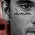 A grayscale close-up of a person's face with visible eye and eyebrow details, partially overlaid by red pixelated shapes on the left side.