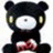 Black bear-like character with white face and red bow tie, seated in a
