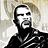 Pixelated grayscale image of a man with short dark hair and beard, wearing a black shirt with white stripes on the shoulder.