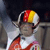 Pixelated static icon of a person wearing a red and yellow helmet with white accents, viewed from the side against a dark background.