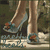Pixelated image of two high-heeled shoes with brown straps and teal accents on a dark background.