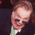 Pixelated image of a person with light brown hair wearing dark sunglasses and a white shirt under a dark jacket, next to green text reading 'Original Icons .com' on a solid background.