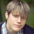 A pixelated image shows a person with light brown hair and a dark jacket over a white shirt on the left, next to pink text reading "I Love Dougie" on a white background.