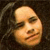 Pixelated close-up of a person's face with closed eyes and a slight smile, set against a dark background with visible hair strands.