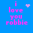 Blue background with pink pixelated text reading "i love you robbie" and a small pink heart symbol above the text.