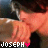 Pixelated static image of a person in orange clothing with text "JOSEPH" and pink heart symbol at bottom left, set against dark background.