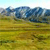 Pixelated landscape with blue sky, dark blue mountains, and yellow-green fields under a light blue sky.