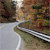 Pixelated static image showing a blurred outdoor scene with a road, greenery, and a vehicle's front section.